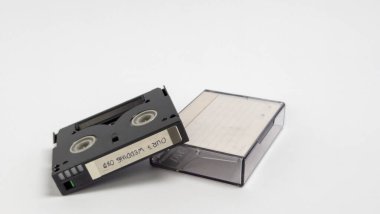 MiniDV video kaseti ve temiz beyaz bir arkaplan karşısında temiz plastik bir kutu. Kasette 