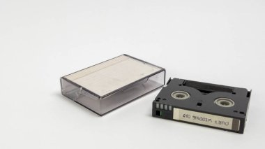 Bir MiniDV kaseti ve temiz plastik kaseti temiz, beyaz bir yüzeye yerleştirilir. Siyah kasette 