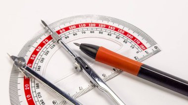 Bir yakın çekim beyaz bir yüzeye yerleştirilmiş bir iletken, pusula ve kalem içerir. Bu araçlar bir tasarım veya eğitim bağlamını önermek üzere konumlandırılmıştır. Bileşim araçların ayrıntılarını ve temiz arkaplanı vurgular, görsel bir uygulama oluşturur