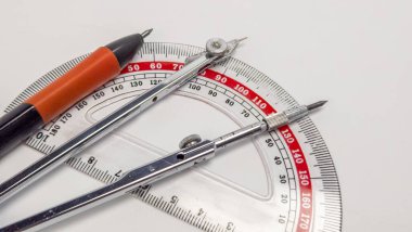 Beyaz bir yüzeyde geometri aletlerini gösteren yakın plan bir çekim. Görüntü bir açıölçer, bir pusula ve bir kalem, matematiksel ve geometrik görevler için gerekli tüm araçları içerir. Araçlar, protrac ile çekici bir bileşim oluşturmak için düzenlenmiştir