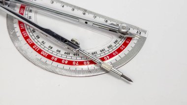 Bu resim, temiz beyaz bir arkaplan üzerine kurulmuş bir pusula ve iletkenin hassasiyet ve işlevselliğini vurgulayan yakın plan görüntülerini göstermektedir. Bileşim, araçların keskin çizgileri, metalik bitiş ve sayısal ayrıntıları vurgular