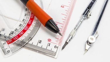 Beyaz bir yüzeye yerleştirilmiş çeşitli taslak araçların yakın plan çekimi. Görüntü bir açıölçer, cetvel, pusula ve mekanik bir kalem sergiler, bunların hepsi geometri, teknik çizim ya da tasarımda kullanılır. Kompozisyon temiz ve iyi aydınlatılmış, yüksek
