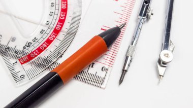 Yakın plan çekimlerde, temiz beyaz bir arkaplanda düzenlenmiş açıölçer, cetvel, pusula ve kalem gibi geometrik araçlar sergilenir. Bu araçlar, bunların taslak veya teknik çizimlerde kullanılmasını önermek üzere konumlandırılmıştır. Görüntü görüntüyü yakalar