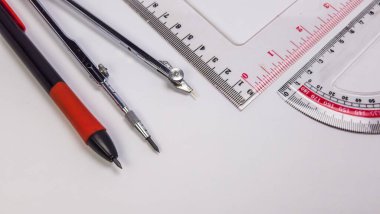 Bu resim, bir pusula, açıölçer ve bir mekanik kalem de dahil olmak üzere, gerekli geometrik araçların ve kırtasiye malzemelerinin bir koleksiyonunu sergiliyor. Kompozisyon temiz ve modern, 