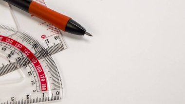 Açık bir plastik iletki ve cetvelin üzerinde duran siyah ve turuncu bir kalemle çekilen bir çekim. Çapraz iletkenin kıvrımlı ve düz kenarlı kırmızı işaretleri ve numaraları var. Arkaplan düz beyaz, metin için yeterli kopya alanı sağlıyor.