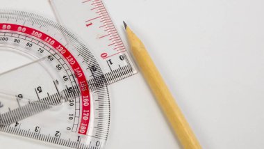 Beyaz arka planda bir kalem, açıölçer ve cetvel içeren yakın plan bir çekim. Bileşim, cetvel ve açıölçerin yanına yerleştirilmiş kalemle geometri araçlarını vurgular. Görüntü iyi aydınlatılmış ve aletler keskin. E için uygun.