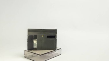 Plastik kutusunun üstüne yerleştirilmiş bir MiniDV video kasetinin yakın çekim çekimi. Siyah bant biraz açık, içerideki kaseti ortaya çıkarıyor. Metin ya da tasarım ögeleri için yeterli kopya alanına sahip temiz beyaz bir arkaplanda izole edilmiş.