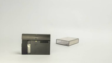 İki miniDV video kaseti ve koruyucu davalarıyla beyaz bir arkaplana karşı çekilmiş bir stüdyo çekimi. Görüntü geçmişin teknolojisini vurguluyor, bu kasetlerin küçük, kompakt formatlarını gösteriyor. Kompozisyon çok net.