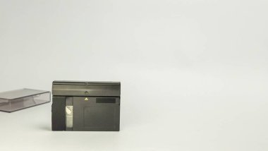 Bu görüntü, bir miniDV kaseti ve onun koruyucu durumunu beyaz arka planda yakın plan görüntüler. Kaset siyah ve kaseti gösteren şeffaf bir bölümü var. Dava çok açık. Kompozisyon basit, o 'yu vurguluyor.