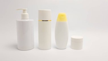 Beyaz bir arka plana karşı bir dizi cilt ürününün temiz, stüdyo çekimi. Koleksiyonda bir pompa şişesi, uzun bir silindirik şişe, sarı kapaklı bir şişe ve küçük bir kavanoz yer alıyor. Görüntü iyi aydınlatılmış, minimalist tasarımı vurguluyor ve... 