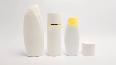 Beyaz kozmetik şişelerden oluşan bir kolleksiyon temiz, beyaz bir arkaplanda düzenlenir. Şişeler, büyük bir şampuan şişesi, uzun bir pompa şişesi, küçük bir oval şişe ve küçük bir kavanoz da dahil olmak üzere şekil ve boyut olarak farklılık göstermektedir. Genel estetik minimalisttir. 