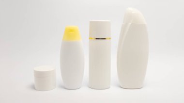 Beyaz kozmetik konteynırlardan oluşan bir koleksiyonun yer aldığı bir stüdyo resmi. Sette küçük bir kavanoz, iki şişe ve uzun bir şeker kutusu yer alıyor. Minimalist kompozisyon, temiz çizgileri ve nötr renk paletini vurgular.