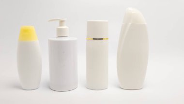 Düz beyaz arka planda dört farklı kozmetik şişenin yer aldığı durgun bir yaşam görüntüsü. Şişeler, bir şampuan şişesi, bir pompa şişesi ve uzun bir silindir şişe de dahil olmak üzere şekil ve boyut olarak değişir. Görüntü temiz ve minimalistik, kimlik