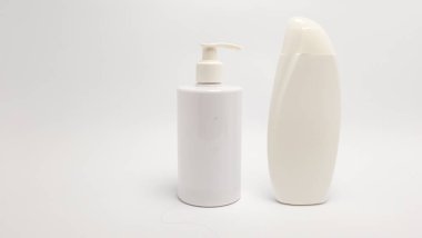 Beyaz arka planda iki beyaz plastik şişe izole edilir. Bir şişenin pompa kutusu var, diğeri ise pürüzsüz, gözyaşı şeklinde bir şişe. Görüntü temiz ve basit, kozmetik, güzellik ve kişisel bakım ürünleri için ideal. Th
