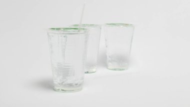 Bir stüdyo çekiminde her biri suyla dolu ve yeşil bir kapakla mühürlenmiş üç temiz plastik bardak yer alır. Bir fincana bir pipet yerleştirilir, diğeri de yere serilir. Bardaklar sığ bir alan derinliğiyle beyaz bir yüzeye yerleştirilmiştir. Resim dolandırıcılığı