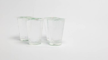 Bu resim, beyaz bir yüzey üzerinde duran suyla dolu birkaç temiz plastik bardak içerir. Bardakların yanına iki pipet konur. Kompozisyon, konunun basitliğini vurgulayan temiz ve minimalistçe. Işıklar yumuşak ve...