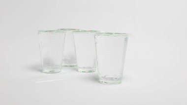 Düz beyaz bir yüzeye dizilmiş dört boş içki bardağının yer aldığı bir stüdyo çekimi. Ön planda iki tane boş pipet var. Bardaklar boş, içecekle doldurulmaya hazır olduklarını gösteriyor. Basit kompozisyon ve döngü