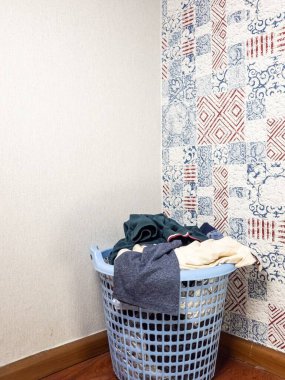 Kirli çamaşırlarla dolu açık mavi bir plastik sepet odanın köşesinde duruyor. Duvar renkli desenli bir duvar kağıdıyla süslenirken, diğer duvar sade. Zemin ahşap tahtalardan yapılmıştır. Görüntü her duyguyu iletir.