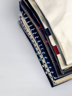 Yakın plan çekimde düzgünce istiflenmiş havlular sergilenir. Havlularda çeşitli renkler ve desenler var. Kompozisyon, temiz beyaz bir zemin üzerine kurulmuş havluların dokularını ve tasarımlarını vurguluyor. Odak noktası aranjman.