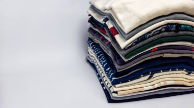 Yakın plan bir stüdyo çekiminde birçok renk ve desen sergilenen katlanmış giysiler sergilenir. Giysiler beyaz bir yüzeyde düzgünce düzenlenmiş. Görüntü bir düzen ve düzen hissi veriyor. Kompozisyon iyi aydınlatılmış ve renkler...