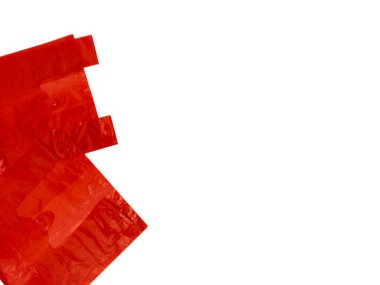 Canlı bir kırmızı plastik alışveriş torbası koleksiyonu temiz beyaz arka plana karşı ustalıkla düzenlenir. Resim, tüketim, atık, geri dönüşüm veya alışveriş gibi konuları resmetmek için mükemmel olan poşetlerin dokusunu ve rengini vurguluyor. Parlak ortak.
