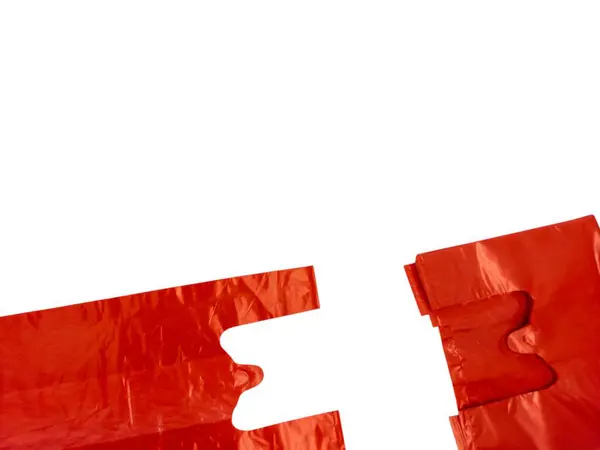 Yakın plan çekimde temiz beyaz arka planda bir çift kırmızı plastik alışveriş torbası görülüyor. Çantalar açık, sapları ve kumaşın parlak dokusunu gösteriyor. Bu resim günlük ortak öğeyi, rengini ve biçimini vurgular.