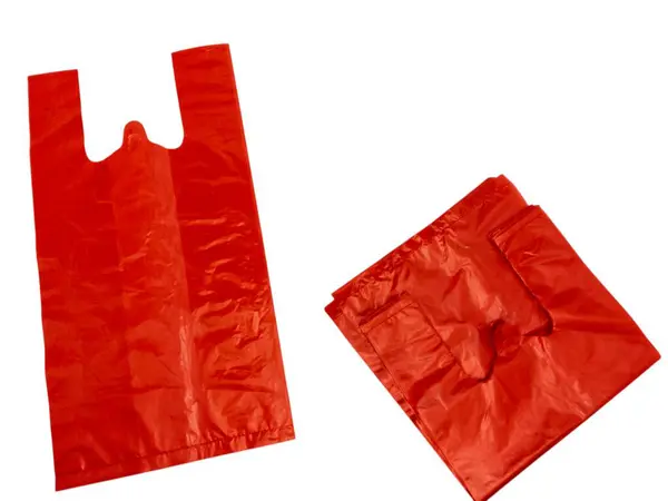 İki kırmızı plastik poşet beyaz arka planda izole edilir. Bir torba açık ve dik, diğeri ise katlanmış. Poşetler ince, parlak plastik malzemeden yapılmış. Görüntü, çantaların şekli ve rengine odaklanmış şekilde iyi aydınlatılmış. Il için mükemmel