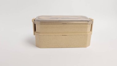 Bej renkli, iki katmanlı bir beslenme çantasının açık kapaklı, minimalist bir tasarımı olan yakın plan bir fotoğrafı. Beslenme çantası çevre dostu malzemeden yapılmış ve bir alet seti içeriyor. Bu resim sağlıklı beslenme, sıfır atık ve şevki göstermek için uygundur.