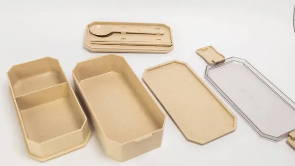Parçalanmış bir çevre dostu bento kutusu seti, bölmeleri, kapakları ve çatal bıçakları sergileniyordu. Set, sürdürülebilir materyaller öneren doğal, bej renkli bir şemaya sahiptir. Görüntü beyaz bir arkaplanda, temiz ve mini bir görüntü sağlıyor.