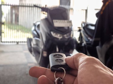 Modern bir scooter 'ın kilidini açmak için motosikletin anahtarlığını kullanan kişi.