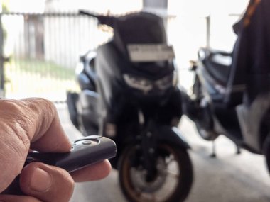 Modern bir scooter 'ın kilidini açmak için motosikletin anahtarlığını kullanan kişi.