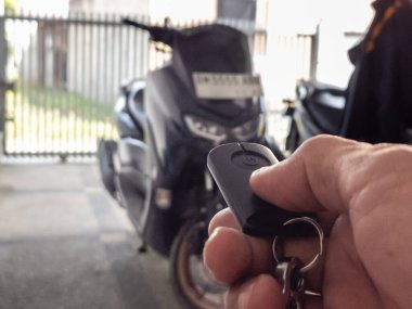 Modern bir scooter 'ın kilidini açmak için motosikletin anahtarlığını kullanan kişi.