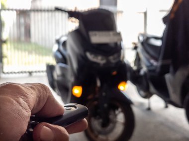 Modern bir scooter 'ın kilidini açmak için motosikletin anahtarlığını kullanan kişi.