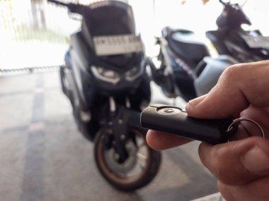 Modern bir scooter 'ın kilidini açmak için motosikletin anahtarlığını kullanan kişi.