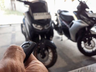 Modern bir scooter 'ın kilidini açmak için motosikletin anahtarlığını kullanan kişi.