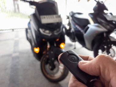 Modern bir scooter 'ın kilidini açmak için motosikletin anahtarlığını kullanan kişi.