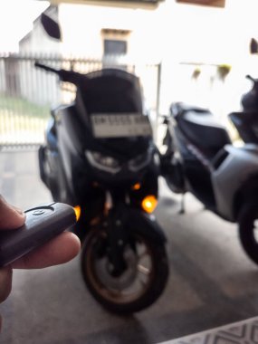 Modern bir scooter 'ın kilidini açmak için motosikletin anahtarlığını kullanan kişi.