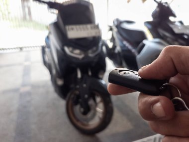 Modern bir scooter 'ın kilidini açmak için motosikletin anahtarlığını kullanan kişi.