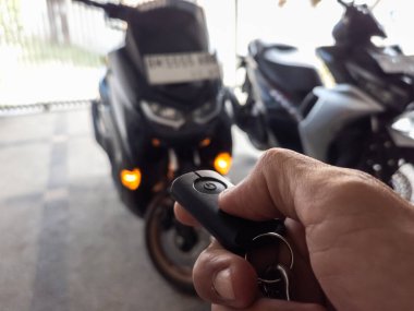 Modern bir scooter 'ın kilidini açmak için motosikletin anahtarlığını kullanan kişi.
