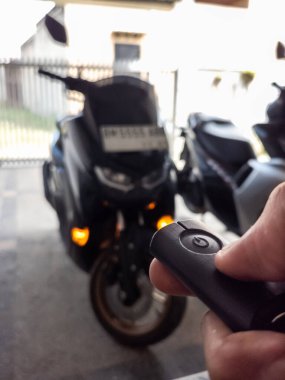 Modern bir scooter 'ın kilidini açmak için motosikletin anahtarlığını kullanan kişi.