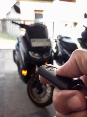 Modern bir scooter 'ın kilidini açmak için motosikletin anahtarlığını kullanan kişi.
