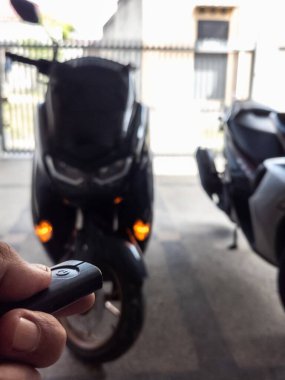Modern bir scooter 'ın kilidini açmak için motosikletin anahtarlığını kullanan kişi.