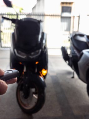 Modern bir scooter 'ın kilidini açmak için motosikletin anahtarlığını kullanan kişi.