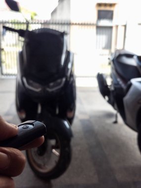 Modern bir scooter 'ın kilidini açmak için motosikletin anahtarlığını kullanan kişi.