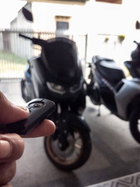 Modern bir scooter 'ın kilidini açmak için motosikletin anahtarlığını kullanan kişi.