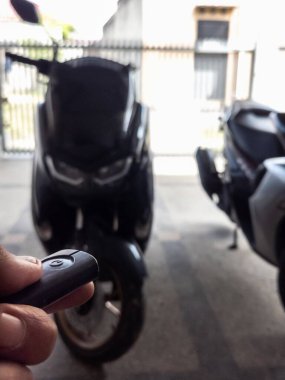 Modern bir scooter 'ın kilidini açmak için motosikletin anahtarlığını kullanan kişi.