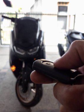 Modern bir scooter 'ın kilidini açmak için motosikletin anahtarlığını kullanan kişi.