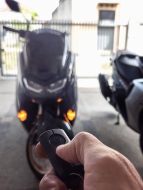Modern bir scooter 'ın kilidini açmak için motosikletin anahtarlığını kullanan kişi.