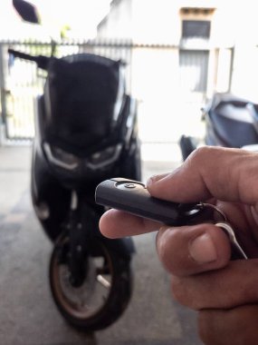 Modern bir scooter 'ın kilidini açmak için motosikletin anahtarlığını kullanan kişi.