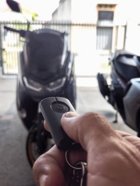 Modern bir scooter 'ın kilidini açmak için motosikletin anahtarlığını kullanan kişi.